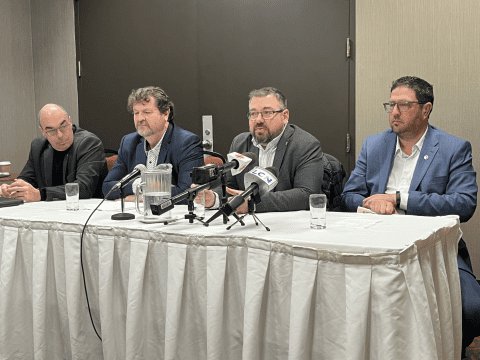 4 personnes assis à une table en conférence de presse